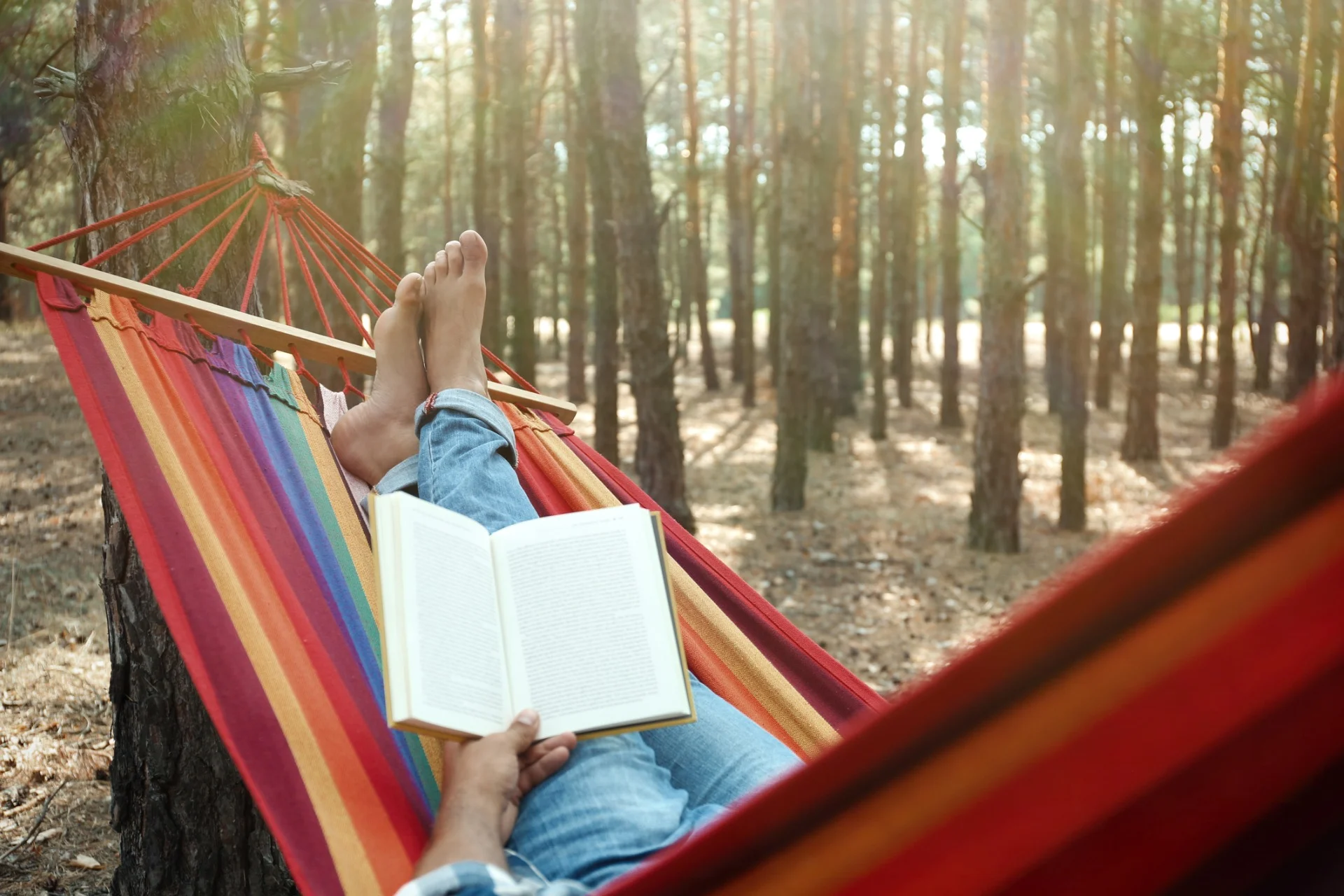man with book relaxing in hammock